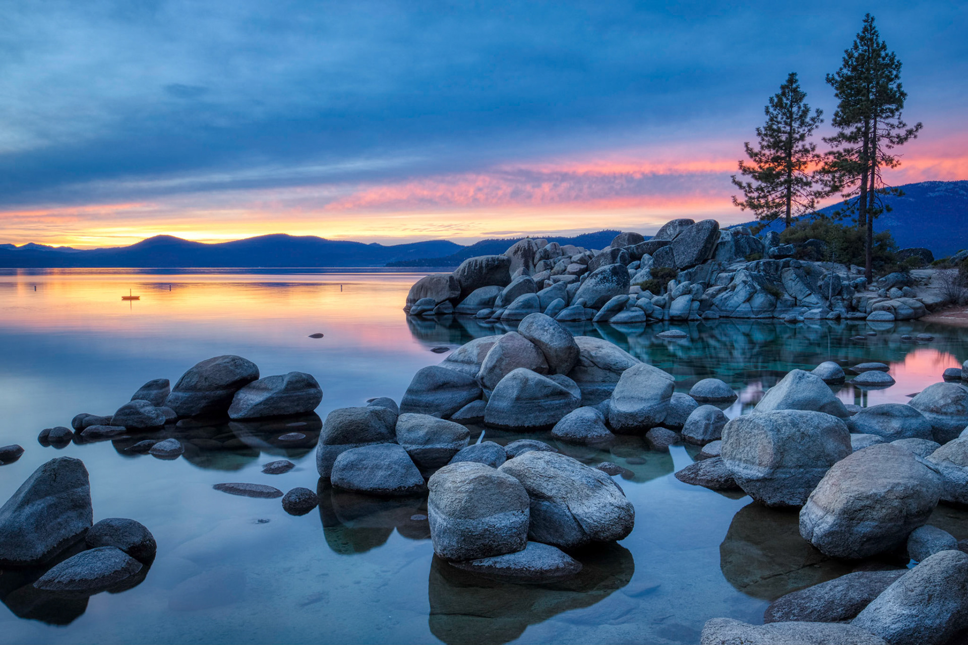 Colorful sky at sunset at Sand Harbor with calm water, beautiful rock formations, and mountains in the background, Lake Tahoe, Carson City, Nevada