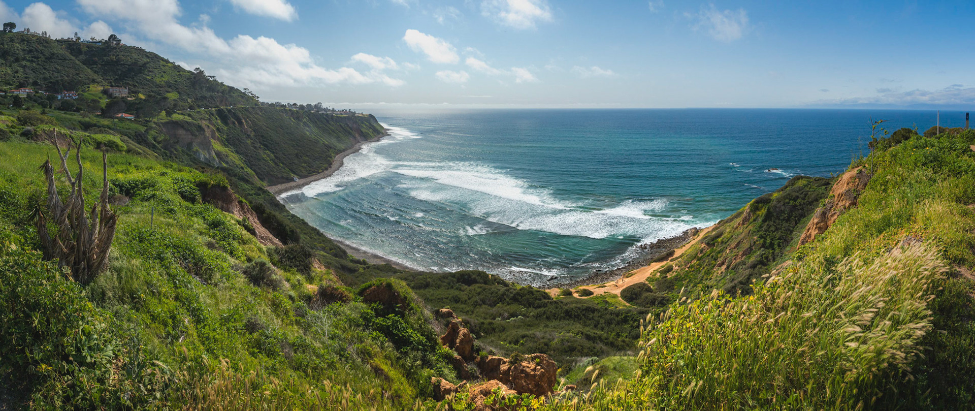 Scenic coastal view of tall cliffs of Bluff Cove covered with vegetation on a sunny spring day with  turquoise colored water and rocky beach, Blufftop Trail, Palos Verdes Estates, California