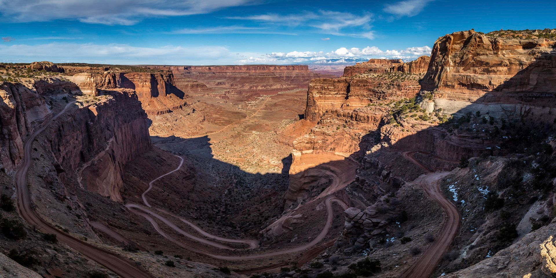 Breathtaking view of rugged Shafer Trail winding down into Shafer Canyon on a sunny day,  Shafer Trail Viewpoint, Island in the Sky District, Canyonlands National Park, Moab, Utah