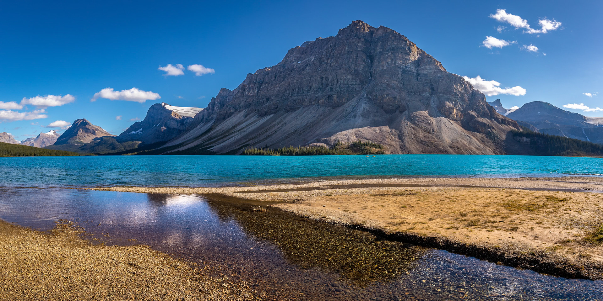 Beautiful view of turquoise colored Bow Lake on a sunny day with Crowfoot Mountain towering in the background and Crowfoot Glacier in the distance, Banff National Park, Alberta, Canada