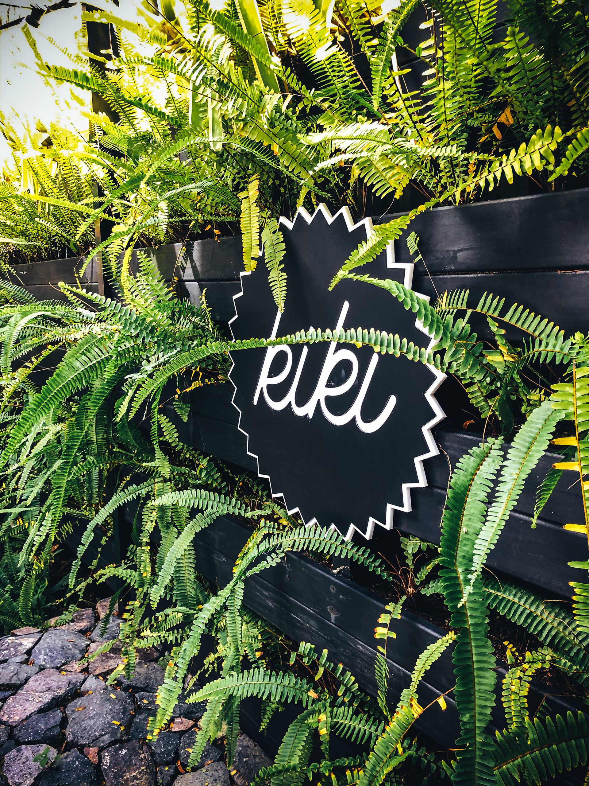An acrylic badge shaped Kiki sign on a garden wall 
