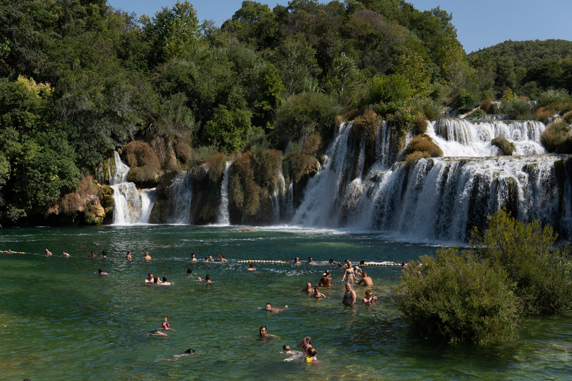 People bathe in the lake in front of the waterfall (Krka national park)