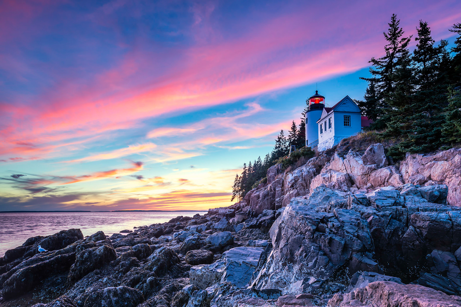 The sun bids adieu, Shadows fill the rocky shore, Warm light paints the sky