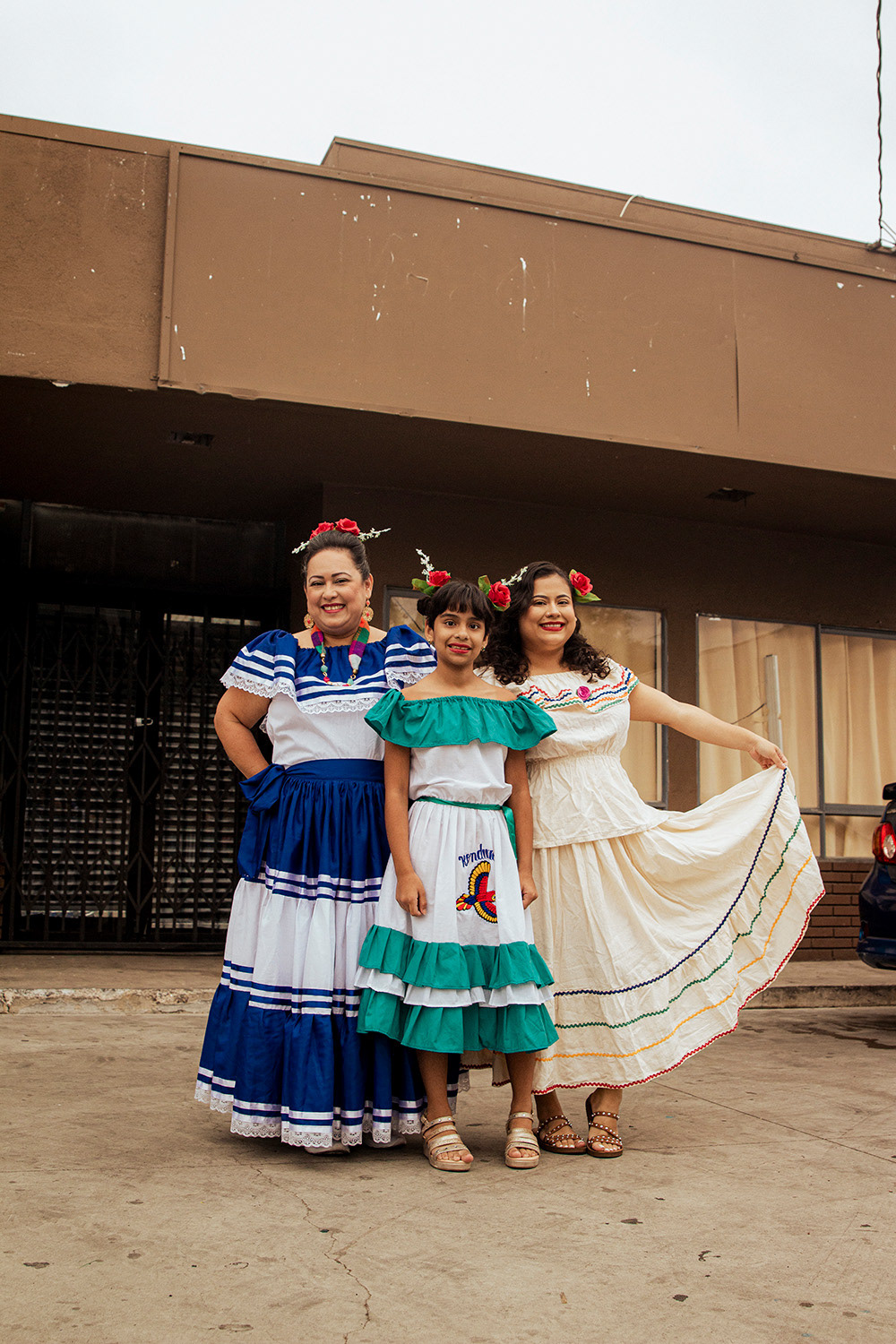 Sindelly, 28, and her sister, Gracia, 10, stand in the parking lot of their grandpa's business with their mother as they're preparing to participate on a float representing Honduras for the Central American Independence Day Parade in Los Angeles on Sunday, September 17th, 2023.