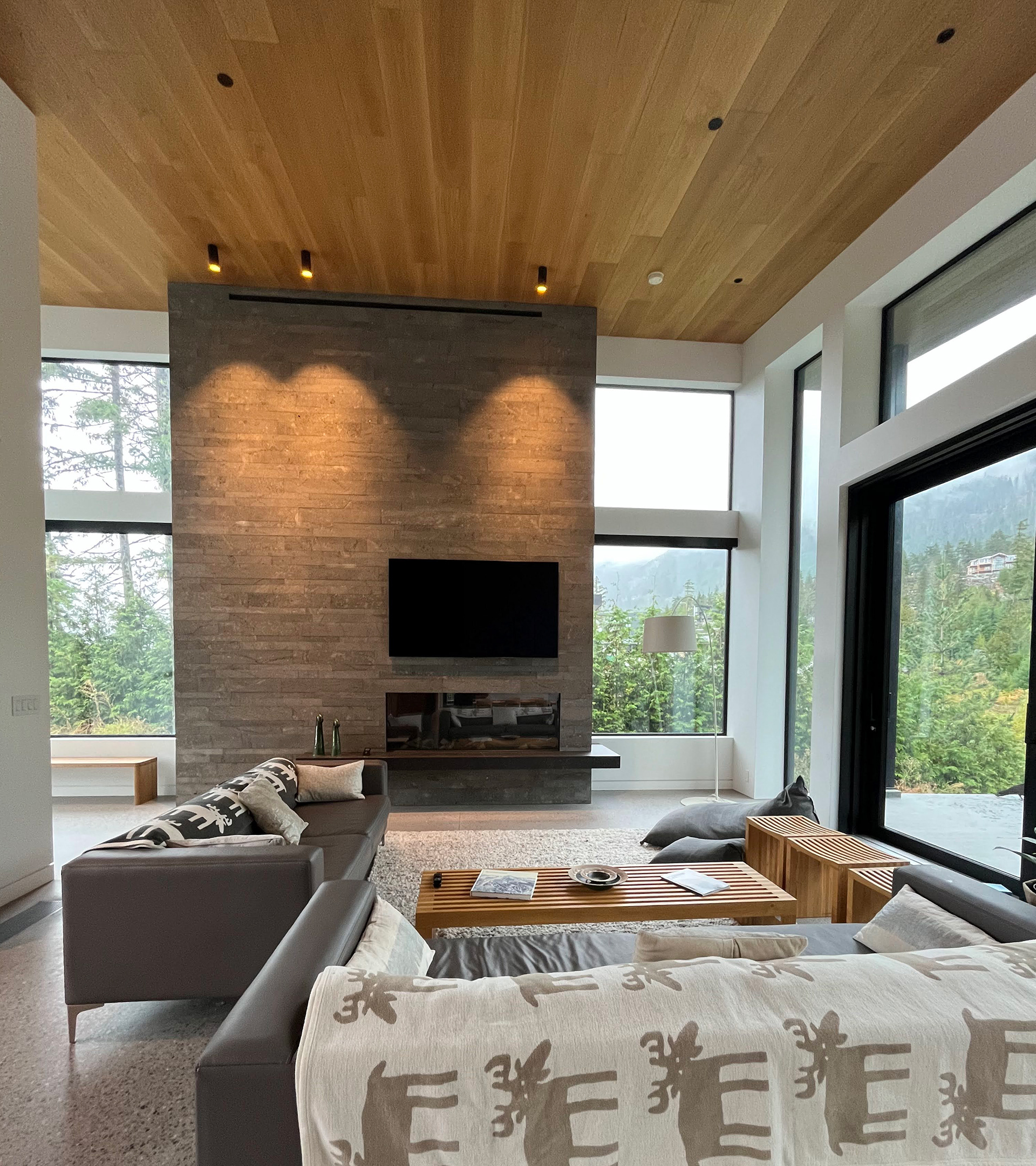 West Coast Modern Living Room at Wedgewoods House in Whistler, BC. Floor to Ceiling Windows, Stone Hearth, Polished Concrete Floors.