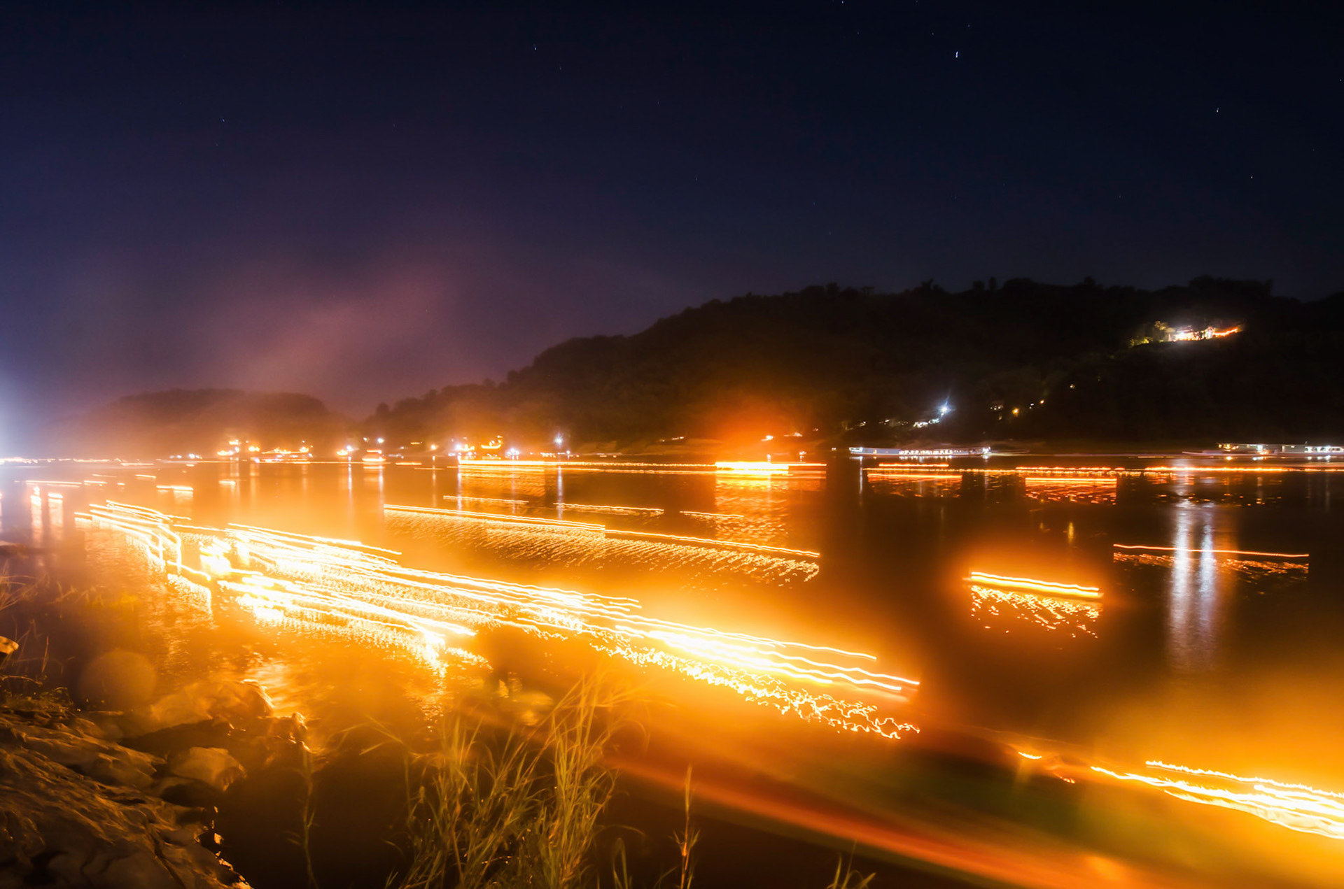 Fire boats and ornaments go down Mekong River stream. Barcos de fogo e ornamentos descem o Rio Mekong. Documentary photographic project about the Fire Boat Festival in Laos. Lanter, culture, tradition, ornament, temple, monk, buddha, buddhism, night, village, story, festa. celebração. Projeto de fotografia documental sobre o Festival do Barco de Fogo no Laos. Lanterna, cultura, tradição, templo, monge, budismo, ornamento, noite, vila, história, party, celebration.