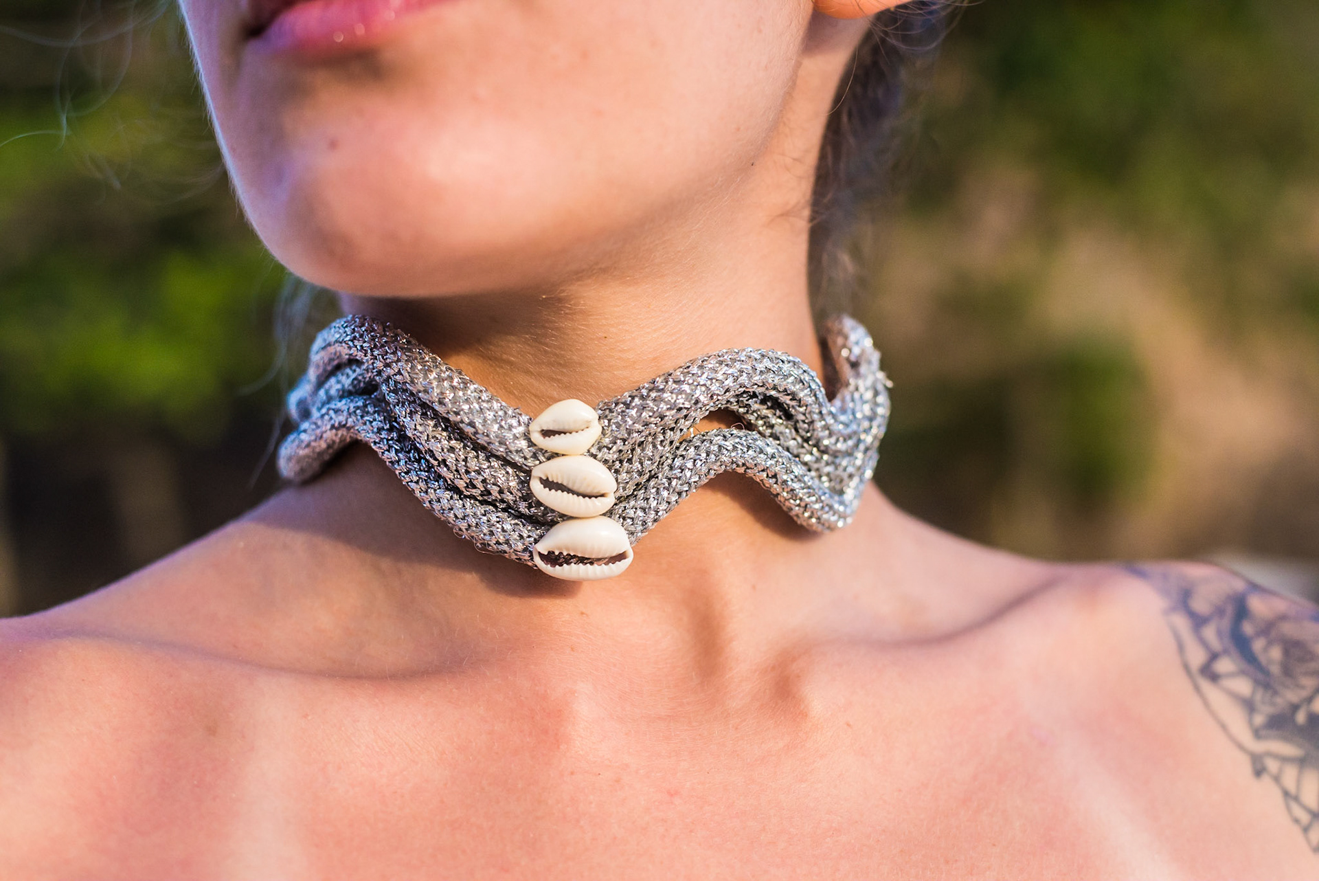 Close-up of silver necklace with shells on female model. Closeup de colar prateado com conchas no pescoço de modelo.