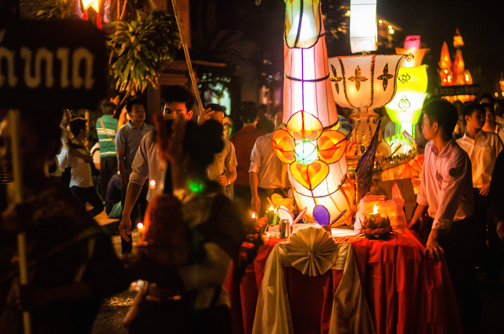 Pessoas carregam barco com velas em procissão. People carry boas with candles on procession. Documentary photographic project about the Fire Boat Festival in Laos. Lanter, culture, tradition, ornament, temple, monk, buddha, buddhism, night, village, story, festa. celebração. Projeto de fotografia documental sobre o Festival do Barco de Fogo no Laos. Lanterna, cultura, tradição, templo, monge, budismo, ornamento, noite, vila, história, party, celebration.