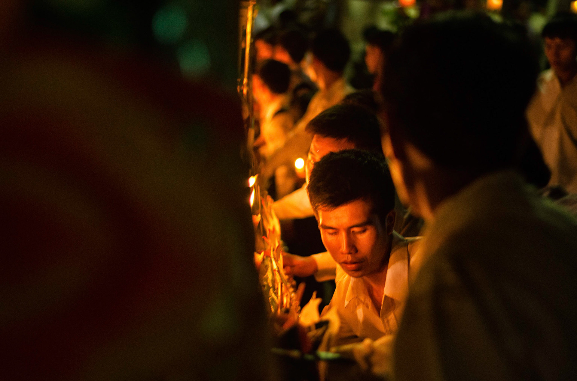 Pessoas carregam barco com velas em procissão. People carry boas with candles on procession. Documentary photographic project about the Fire Boat Festival in Laos. Lanter, culture, tradition, ornament, temple, monk, buddha, buddhism, night, village, story, festa. celebração. Projeto de fotografia documental sobre o Festival do Barco de Fogo no Laos. Lanterna, cultura, tradição, templo, monge, budismo, ornamento, noite, vila, história, party, celebration.