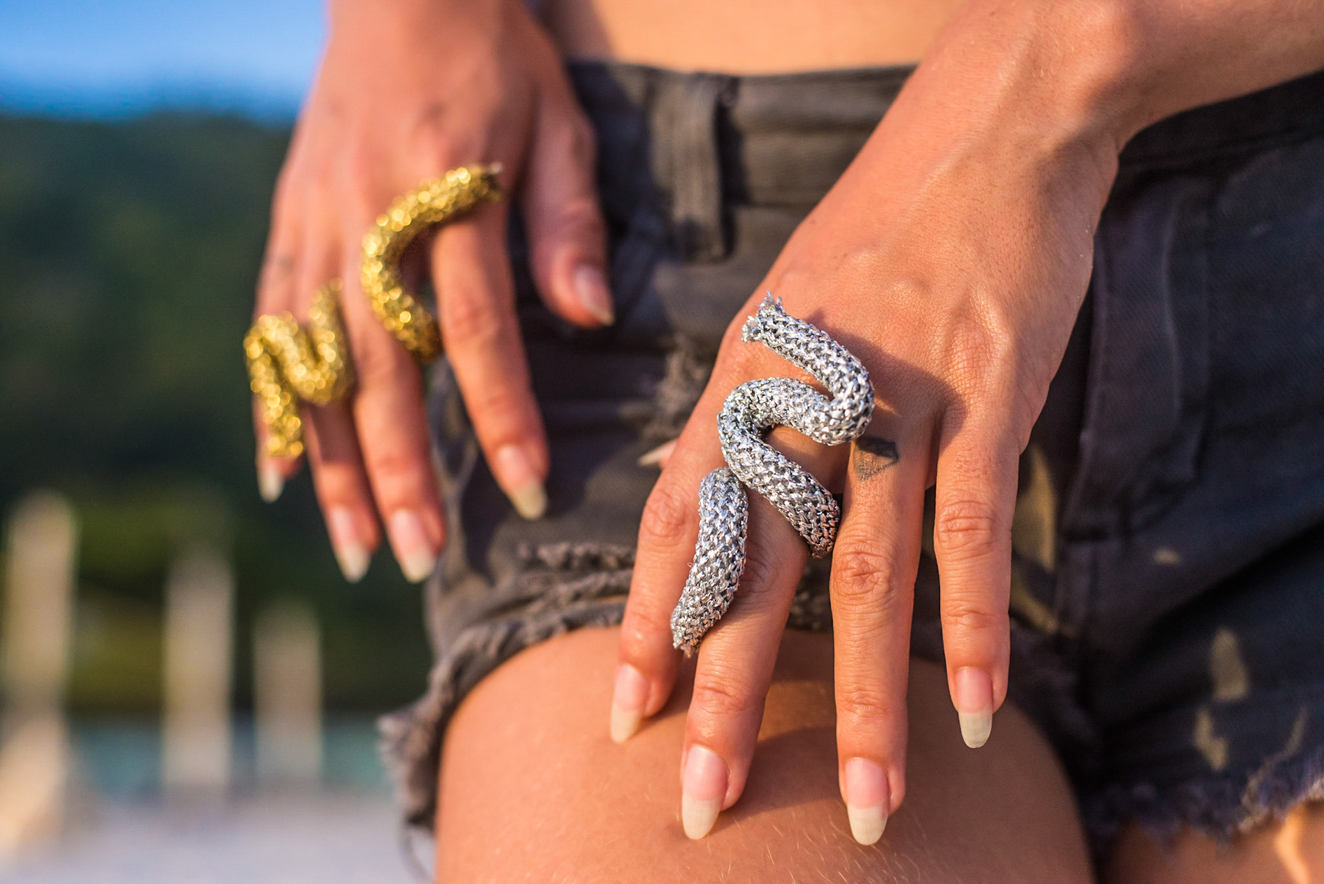 Hands closeup with one ring each, golden and silve. Close das mãos com um anel cada, dourado e prateado. woman with large white trousers and golden shell necklace stares at camera. mulher de calça grande e colar concha dourado olha para camera. fashion photography, designer, clothes, dress, accessory, product, still, brand, lookbook, shooting, vibrant, colorful, beach, creative, catalogue, outfit, look.fotografia de moda, design, roupa, vestido, acessório, produto, still, marca, vibrante, colorida, praia, catálogo, rio de janeiro.