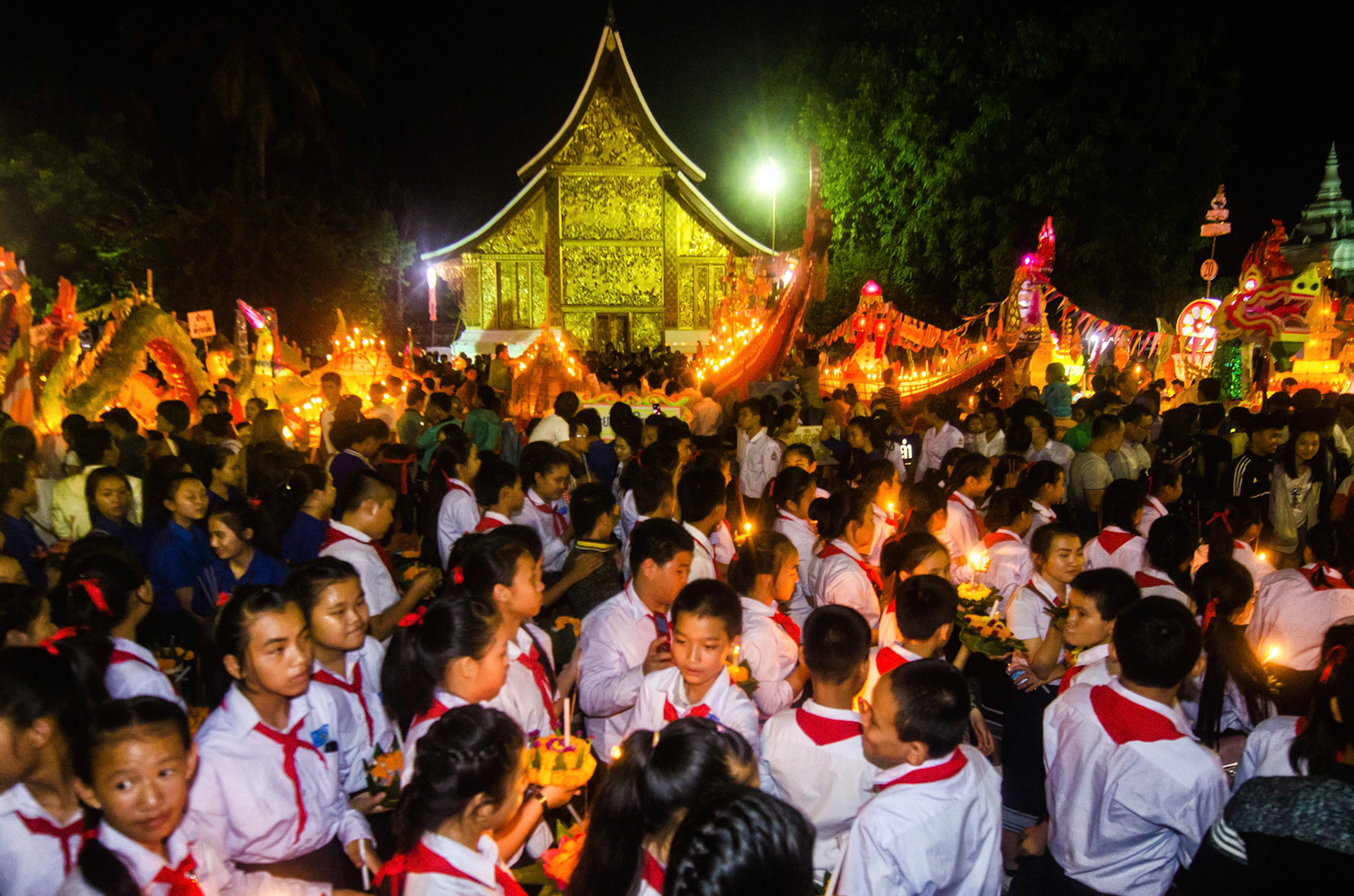 Children gather and celebrate in a party with all the boats reunited. Crianças se juntam e celebram numa festa com todos os barcos reunídos. Documentary photographic project about the Fire Boat Festival in Laos. Lanter, culture, tradition, ornament, temple, monk, buddha, buddhism, night, village, story, festa. celebração. Projeto de fotografia documental sobre o Festival do Barco de Fogo no Laos. Lanterna, cultura, tradição, templo, monge, budismo, ornamento, noite, vila, história, party, celebration.