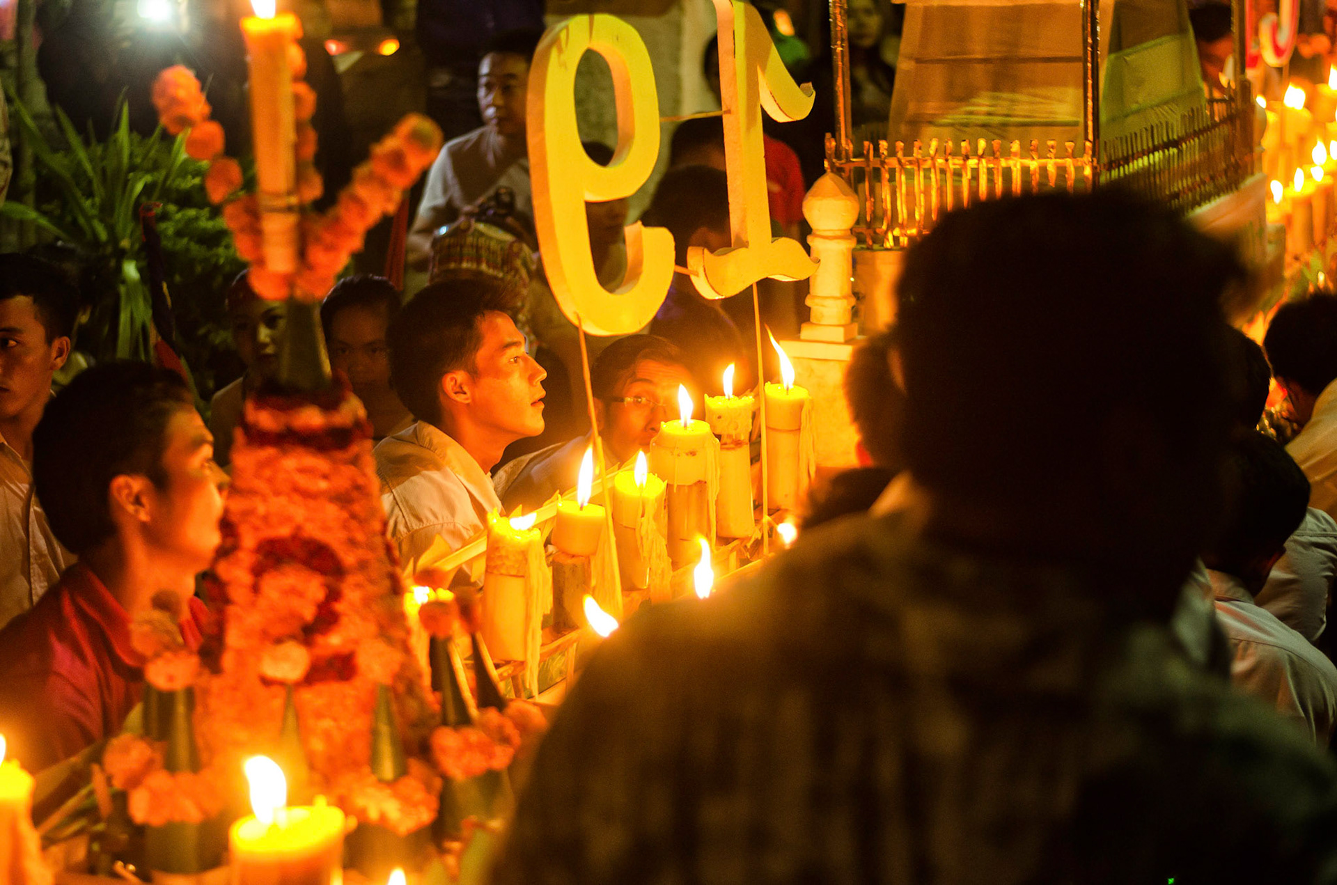 Pessoas carregam barco com velas em procissão. People carry boas with candles on procession. Documentary photographic project about the Fire Boat Festival in Laos. Lanter, culture, tradition, ornament, temple, monk, buddha, buddhism, night, village, story, festa. celebração. Projeto de fotografia documental sobre o Festival do Barco de Fogo no Laos. Lanterna, cultura, tradição, templo, monge, budismo, ornamento, noite, vila, história, party, celebration.