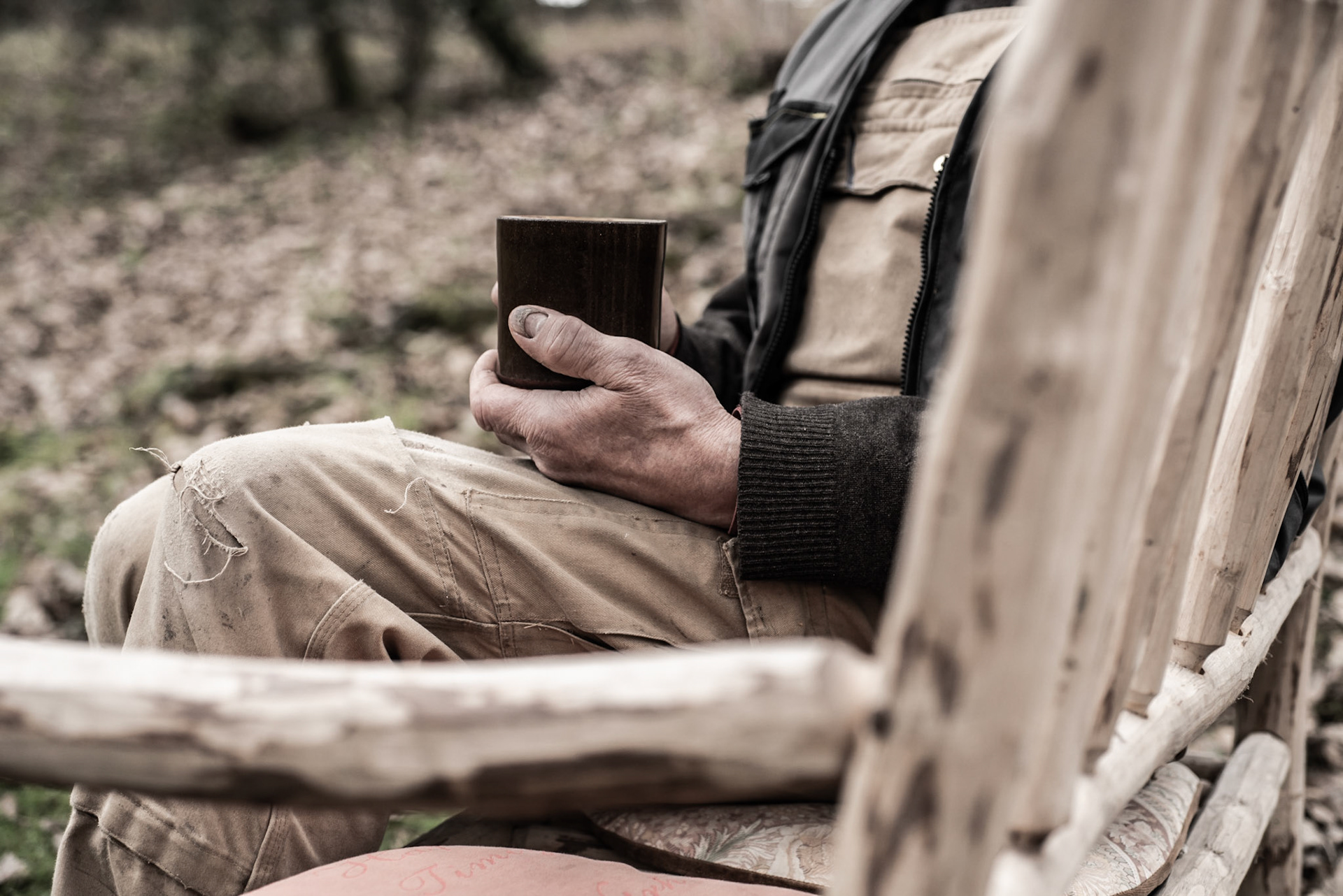 Image dipicting slow living. Person seated on a bench holding a cup