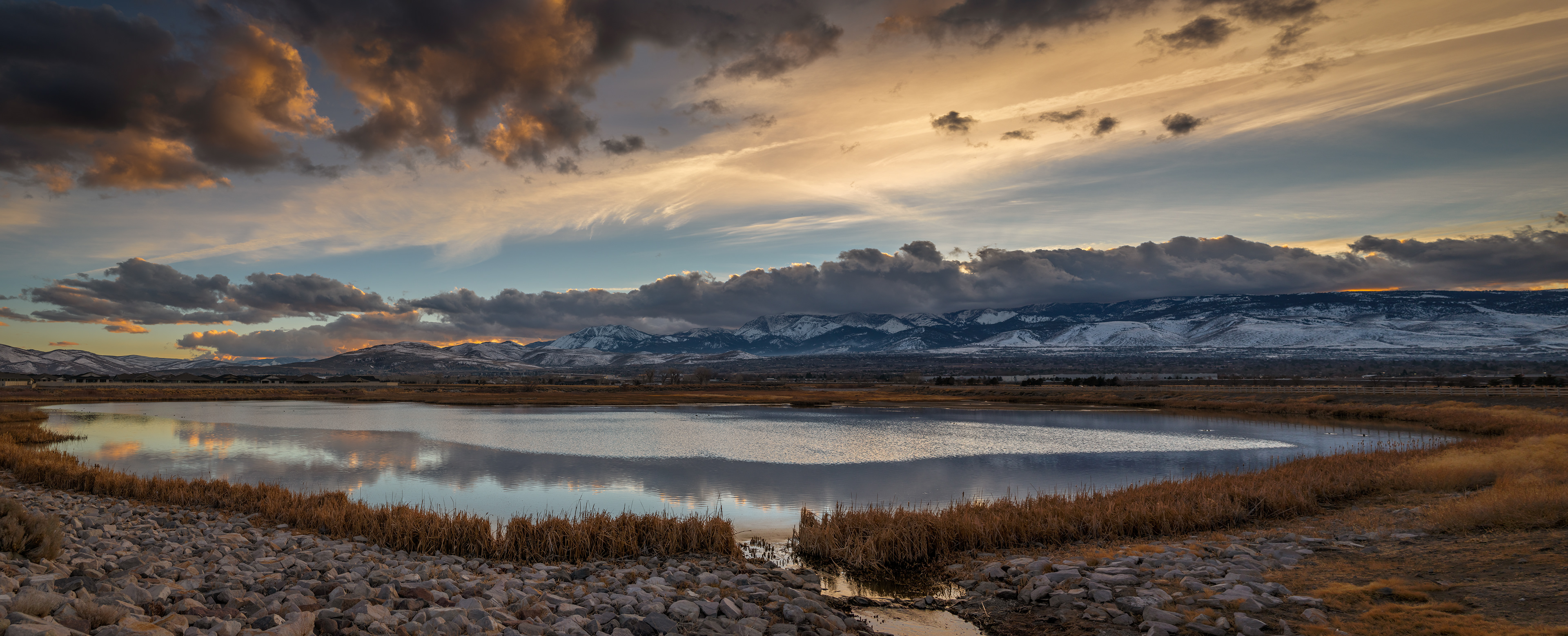 Image of a retention pond in Reno with Mount Rose and Slide Mountain and cloud cover in the background. Panorama.