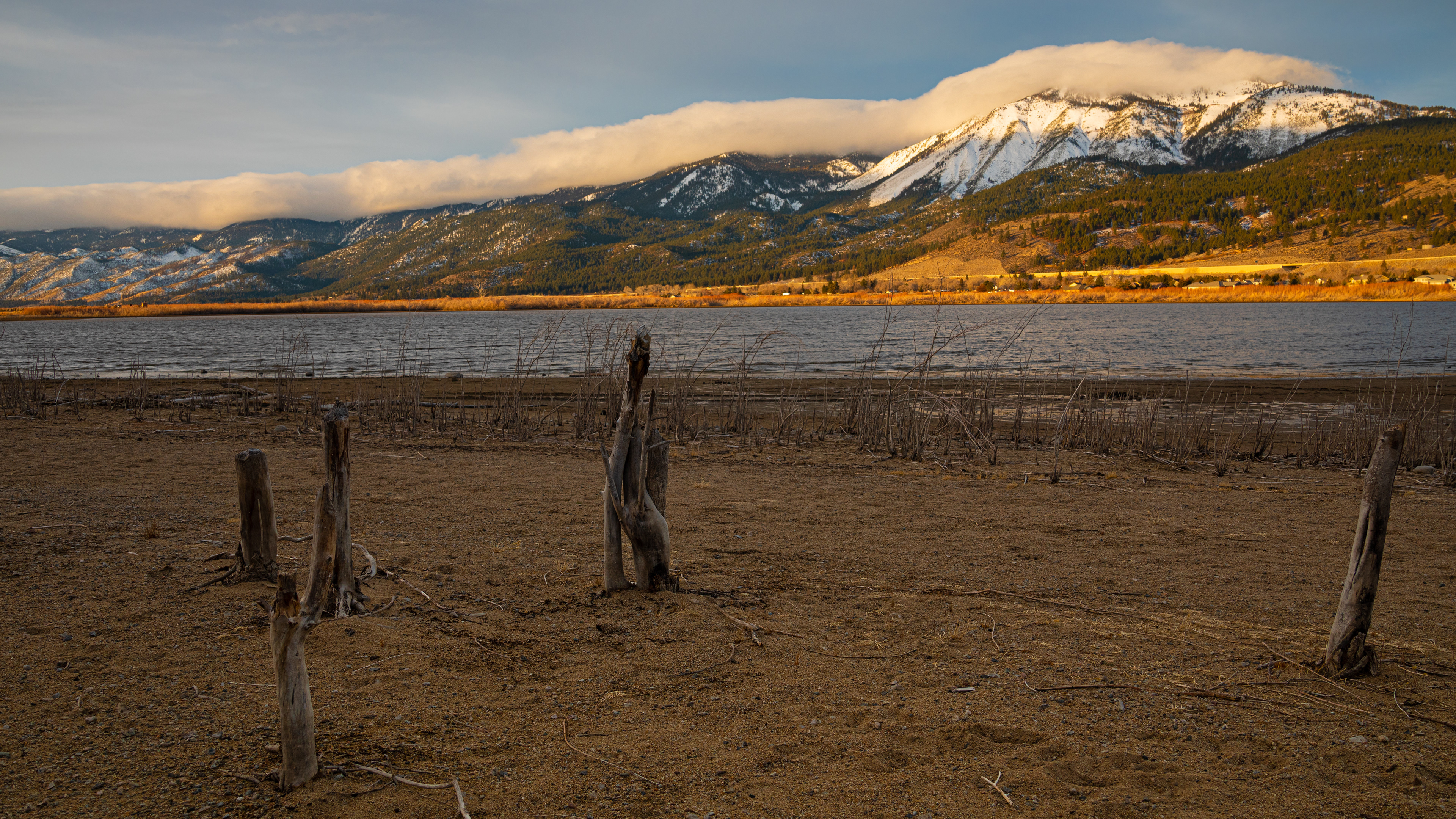 Slide Mountain with cloud cover, and Washoe Lake and the shoreline in the foreground.