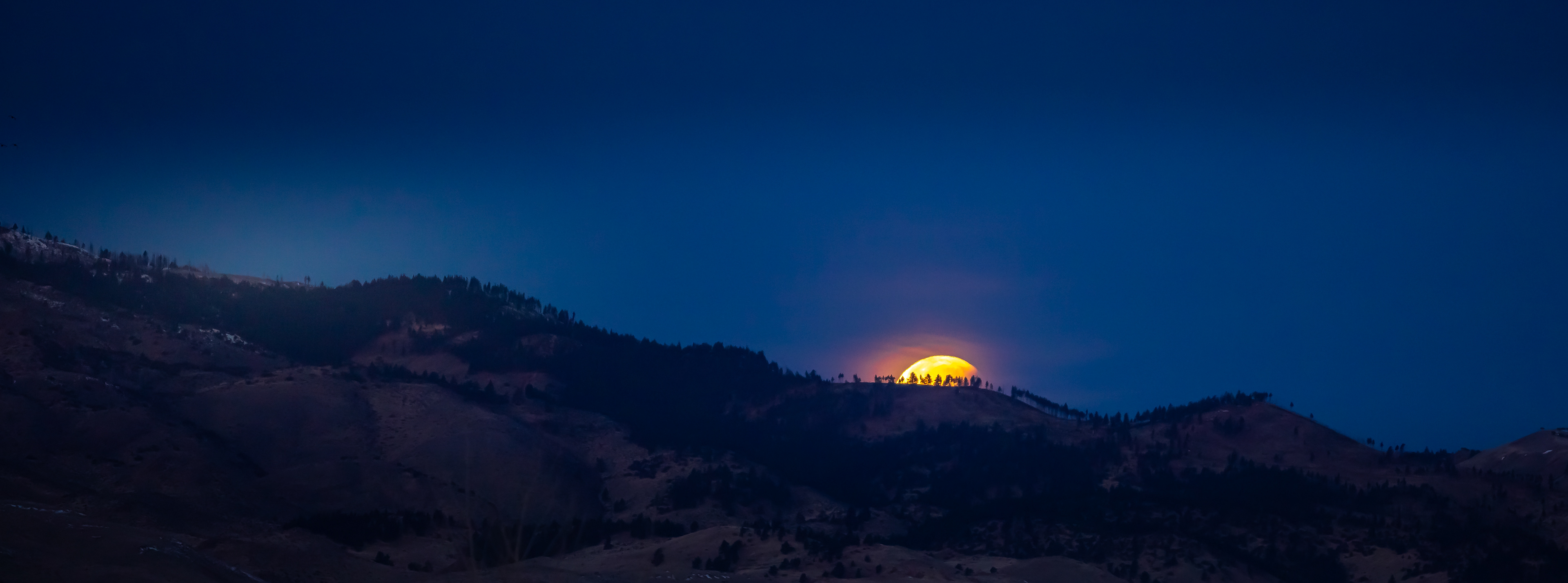 The moon setting behind the mountains after a Lunar Eclipse.