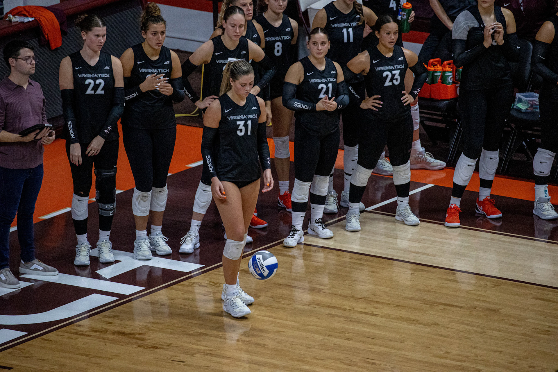 Outside hitter Payton Woods prepares to serve, focusing as she readies to put the ball in play