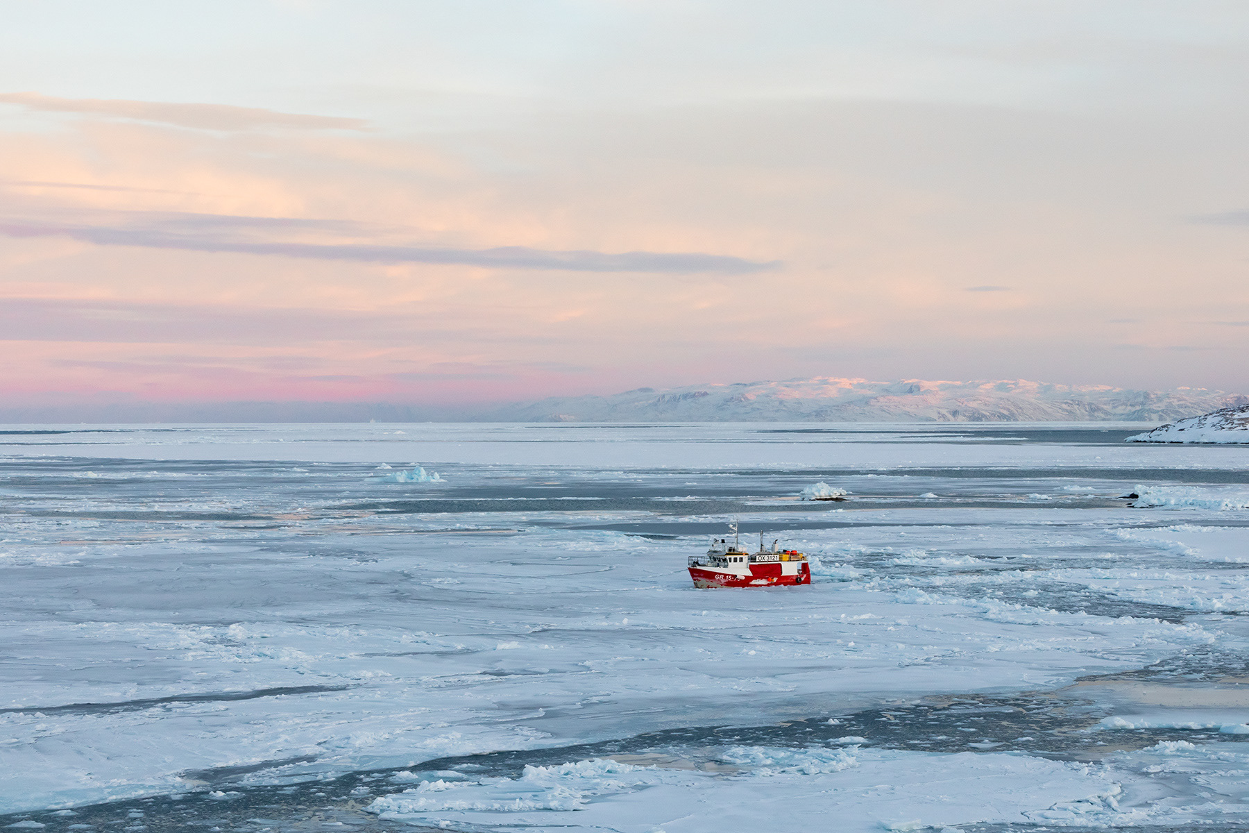 Large fishing vessel breaking up the ice for smaller boats.