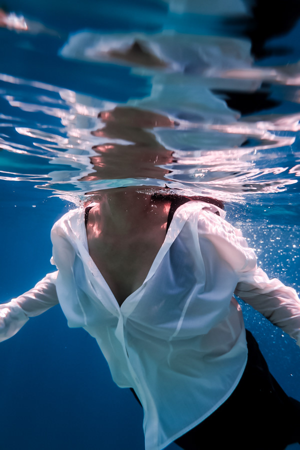 Eleftheria Bargiota partially submerged underwater with a floating white shirt, created for the “Treis Epoxes” album. 