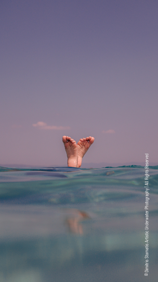 Feet emerging from the water while the body floats below the surface.