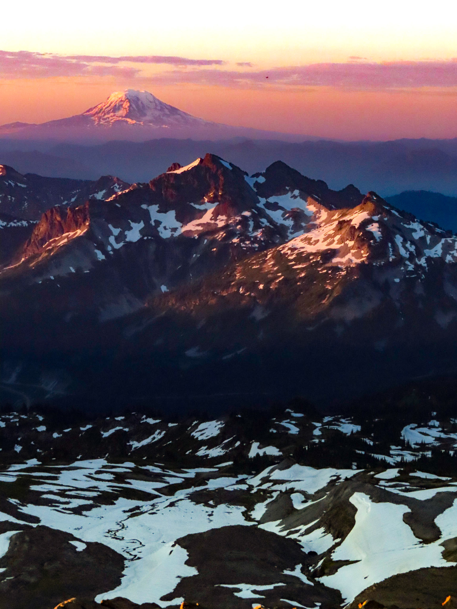 The Tatoosh Range illuminated in the early morning sunrise, with the Mt Adams volcano looming in the bakcground.