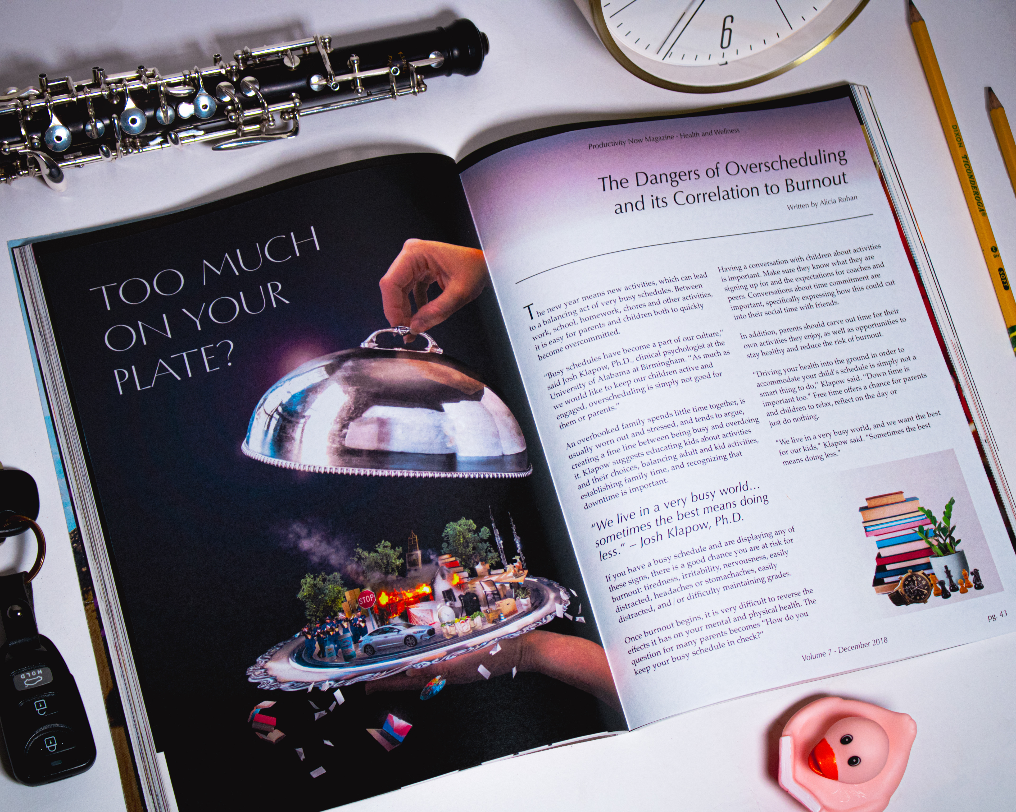 Magazine reading "Too Much On Your Plate?" surrounded by an assortment of objects such as pencils, a clock, and an oboe.