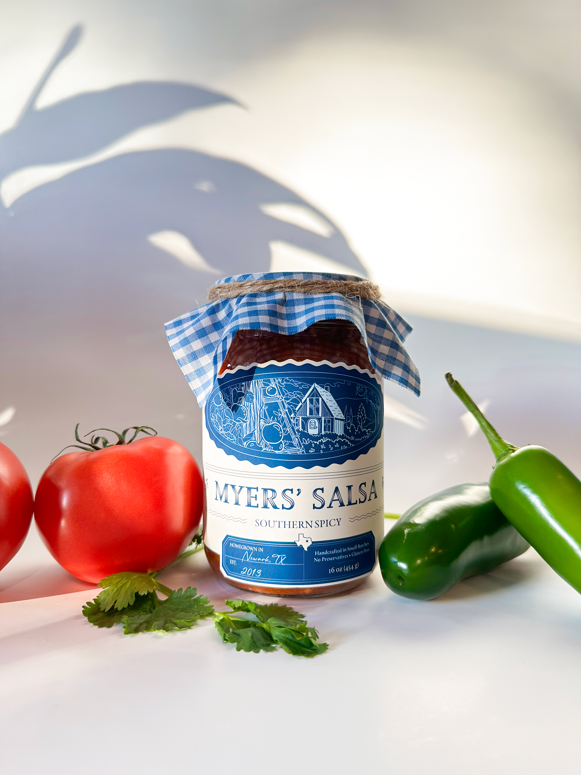 An image of a salsa jar with a tomato and jalapeños.