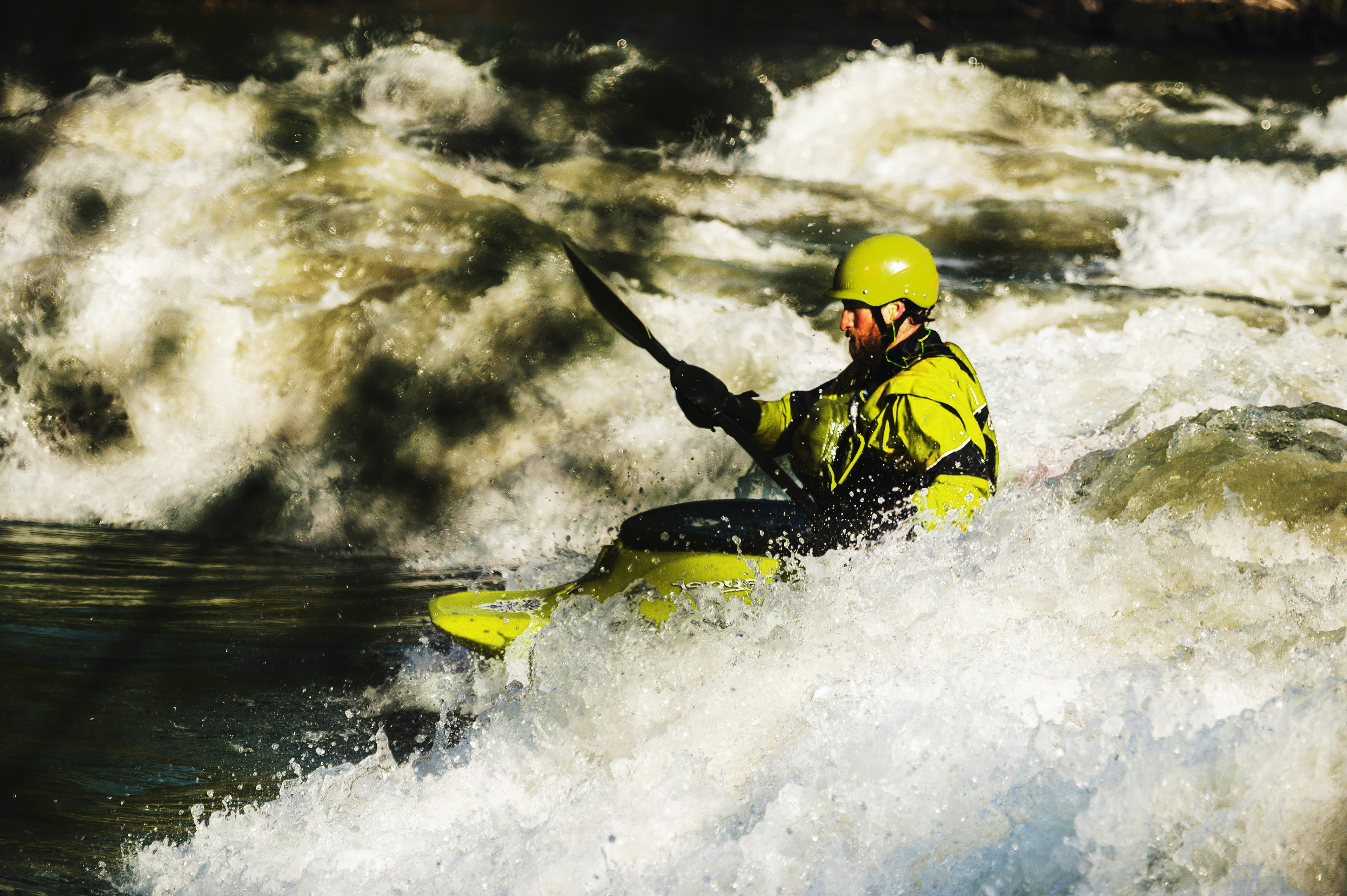 A man steers a kayak in turbulent water.