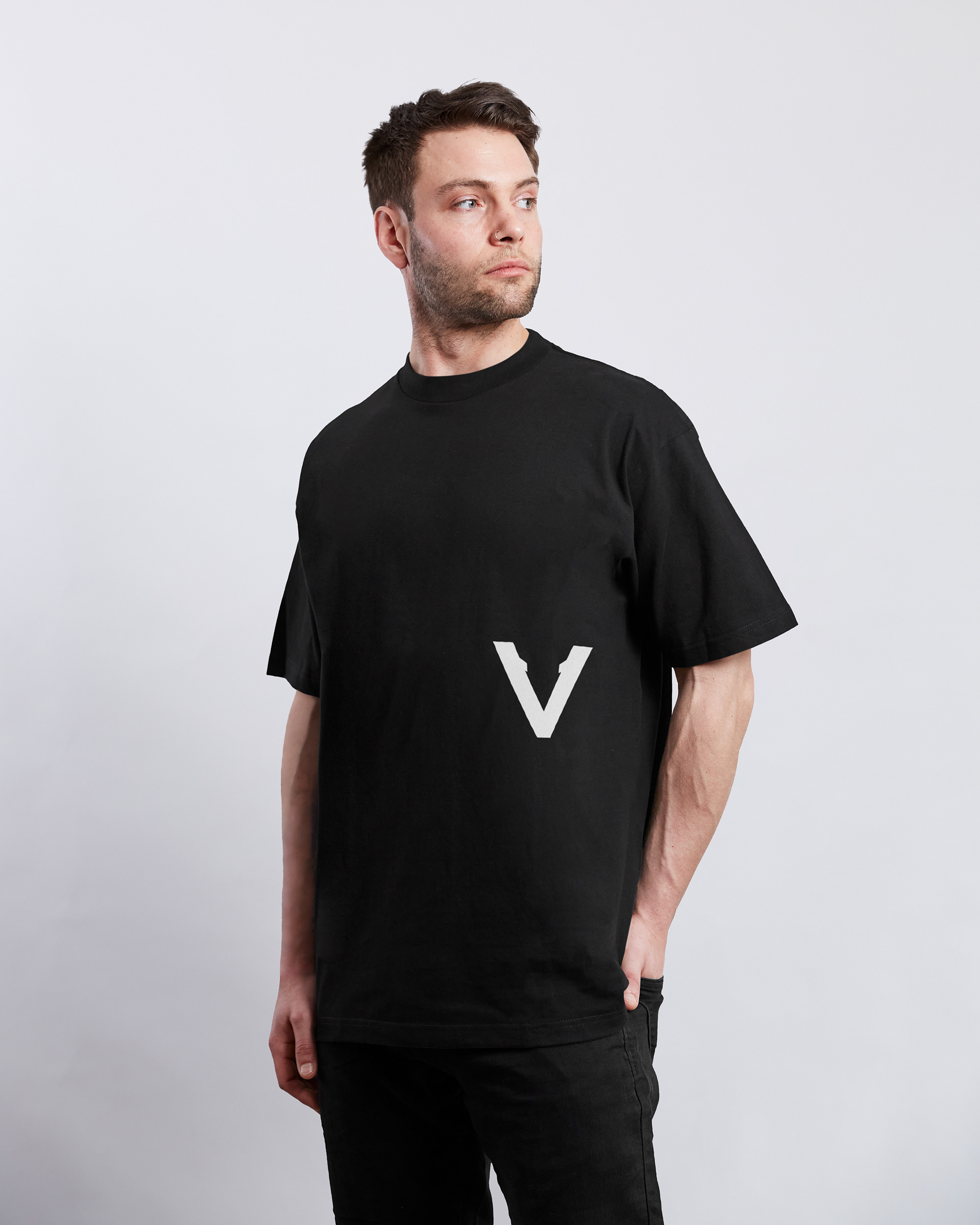 Vinciani oversized black T-shirt featuring the signature white V emblem positioned on the lower front, crafted with a heavyweight premium streetwear silhouette and minimalist contemporary design.