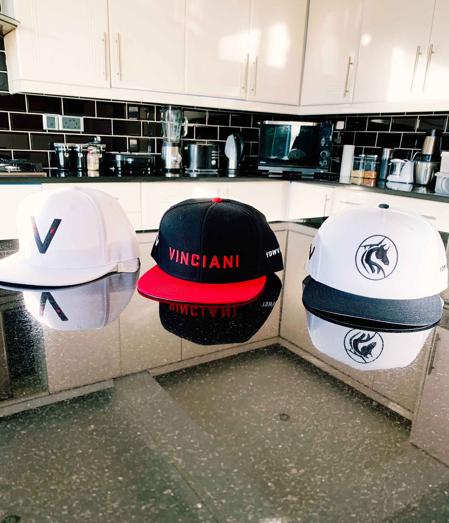 Vinciani caps displayed on a kitchen countertop featuring the horse emblem, Vinciani Code Red Cap, and V-Mark logo variations.