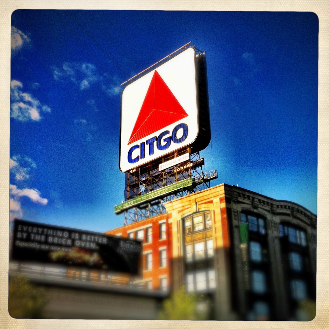 50. Citgo Sign ••• We’ve reached the halfway point of the series and what better way to celebrate the milestone than highlight a sign some would call the granddaddy of them all. Located in the heart of Kenmore Square, the iconic Citgo Sign has become a landmark on the Boston skyline. Not only is it visible over the left field wall from Fenway Park, but runners of the Boston Marathon can spot it at the 20th mile mark. It was originally erected in 1940 featuring the “Cities Service” logo, then replaced by the now familiar Citgo “trimark” in 1965. The sign was renovated in the 1980s after efforts to remove it faced fierce opposition. The double-sided sign is said to be the largest in New England (60-feet by 60-feet), and illuminated from dusk to midnight by 9,000 linear feet of animated LED stripe units. Before the LEDs were installed in 2005, it contained more than five miles of neon tubes. A fellow by the name of Marty Foley has been the sign’s caretaker since 1965. (#50 of 100 in the Boston Signage Project)