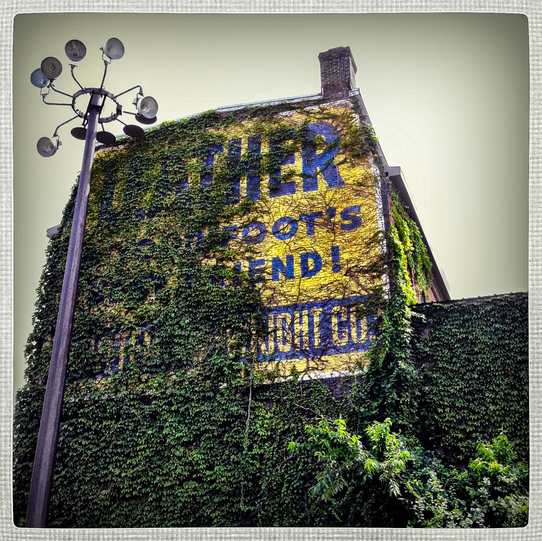 58. Whittemore-Wright Sign ••• Whittemore-Wright is an old tanning oil company that's been around since 1908. Three sides of their brick factory in Charlestown is covered with painted signs, but this side is the most interesting. Before it was devoured by ivy, the sign read "Leather is your foot's best friend". (#58 of 100 in the Boston Signage Project)
