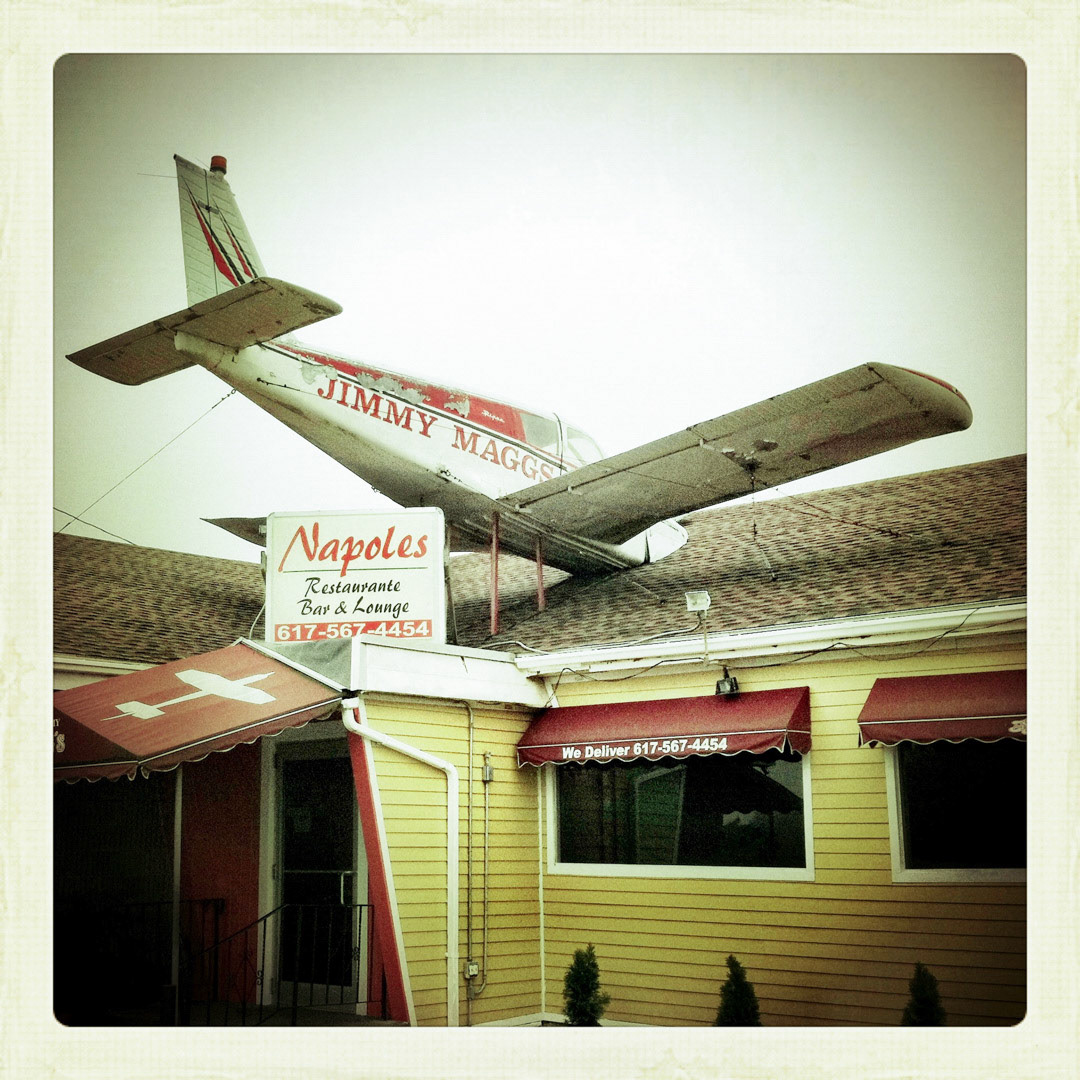 75. Jimmy Maggs Napoles Airplane Sign ••• Across the street from the Suffolk Downs station in East Boston is Jimmy Maggs "Napoles", a typical restaurant and lounge, aside from the protruding Piper prop plane with its nose buried in the roof. (#75 of 100 in the Boston Signage Project)