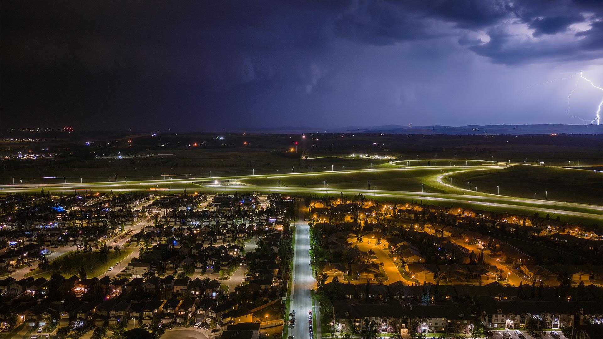 Night time aerial photo, with northbound storm approaching, from over the neighborhood of Bridlewood, Calgary, AB - August 23rd
