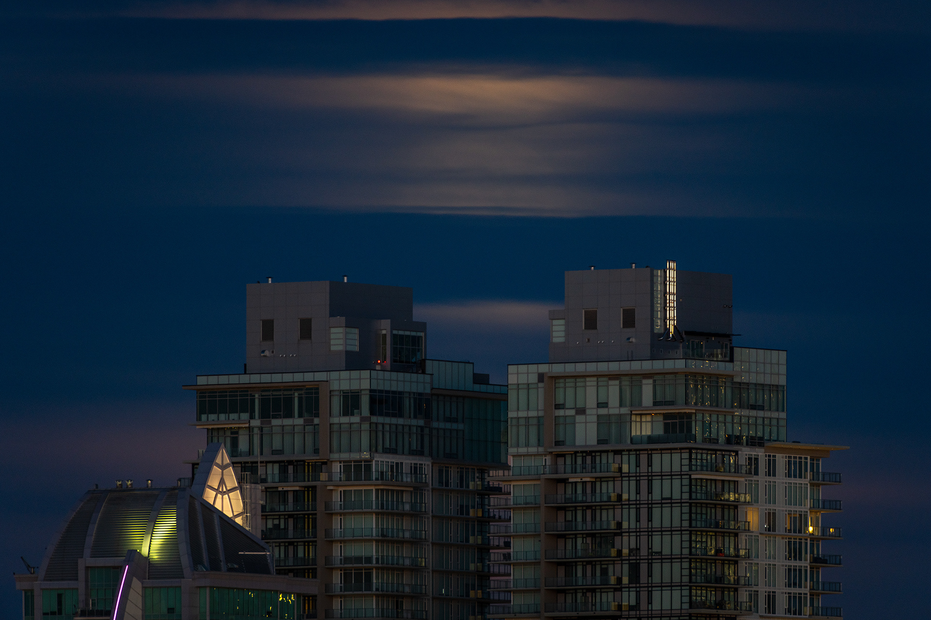 Moonset (Full phase @ 99.3%, elevation 3.6 degrees) (Nautical Twilight, Sun elevation -6.5 degrees) over twin tower downtown buildings, Tom Campbell's Hill Natural Park, Calgary, AB