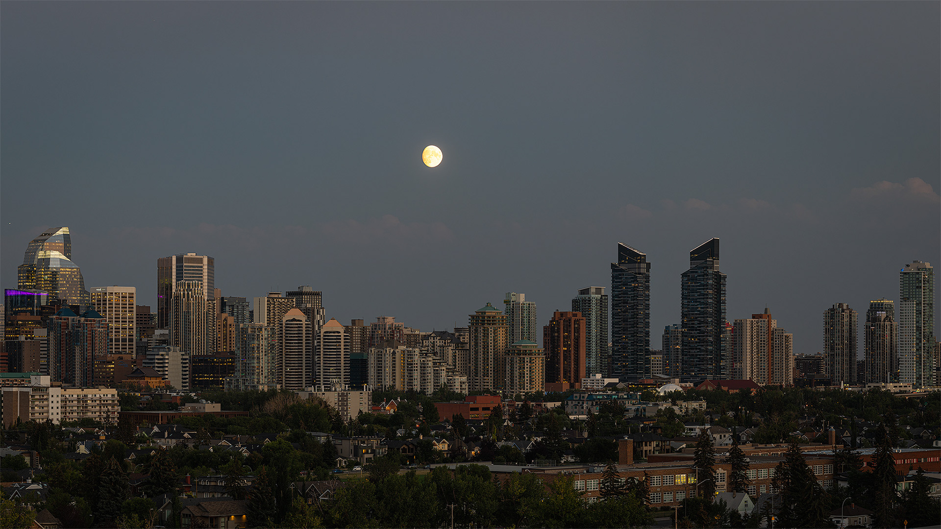 16x9 Cityscape of the Downtown West End Calgary skyline at Sunset/Moonrise, from West Hillhurst off-leash area (Grasshopper Hill), Calgary, AB