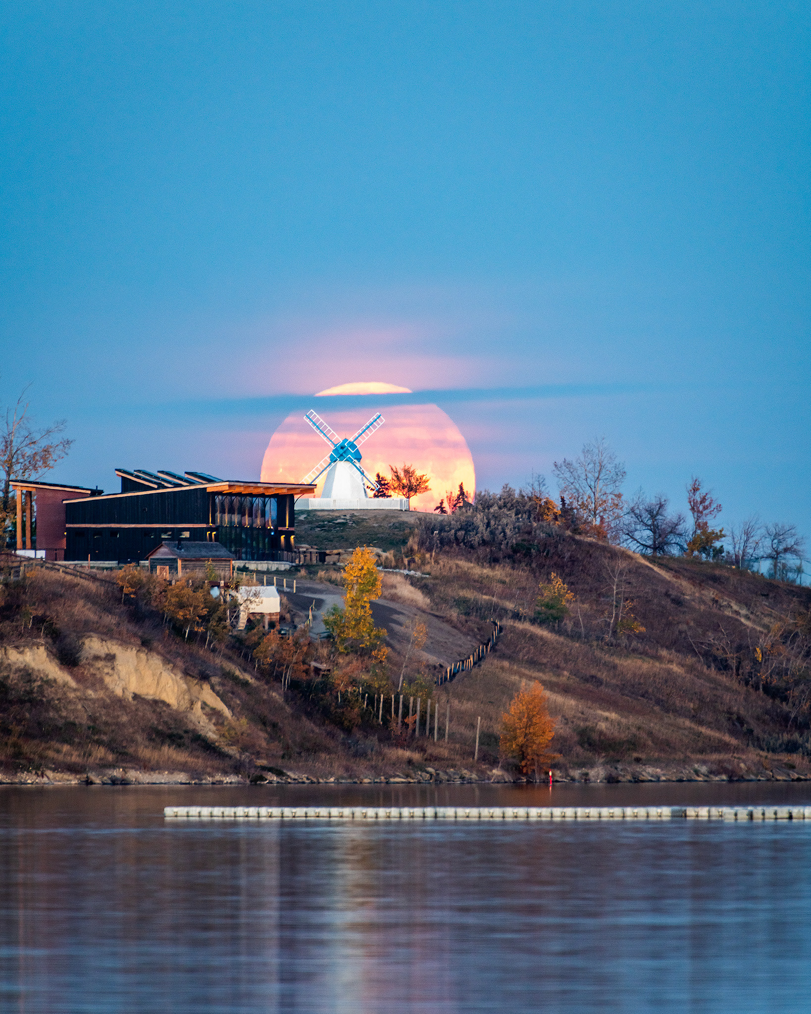 Full Moon (Hunter's Moon) rising behind the Bruderheim Windmill (a Heritage building in Heritage Park), from the water's edge near South Glenmore Park, Calgary, AB - October 9th, 2022 (7:16 PM, 34 Mp)