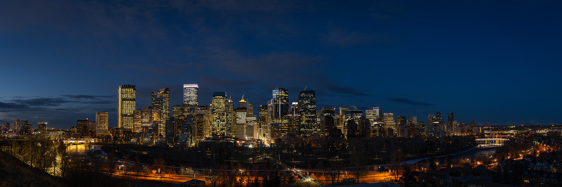 3x1 Panoramic Cityscape (9 shot) of the downtown skyline, Prince's Island Park, Bow River, Memorial Dr., Center St. Bridge, and Peace Bridge [pre sunrise, Nautical Twilight (sun altitude -7.7 degrees)], from Crescent Heights Lookout Point, Calgary, AB