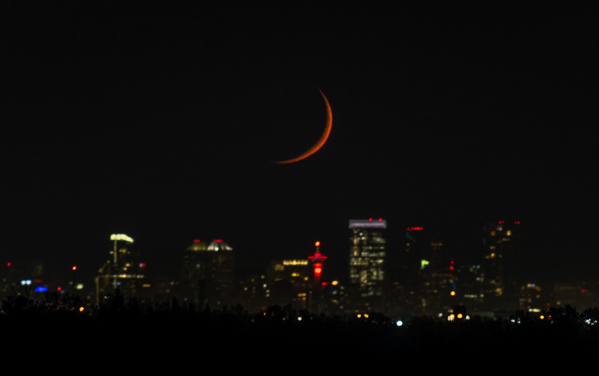 Moonset over the downtown skyline (Waxing Crescent phase @ 6.9%, elevation 1.27 degrees) (Astronomical Twilight, Sun elevation -14.3 degrees) from highway 22X near Indus, AB