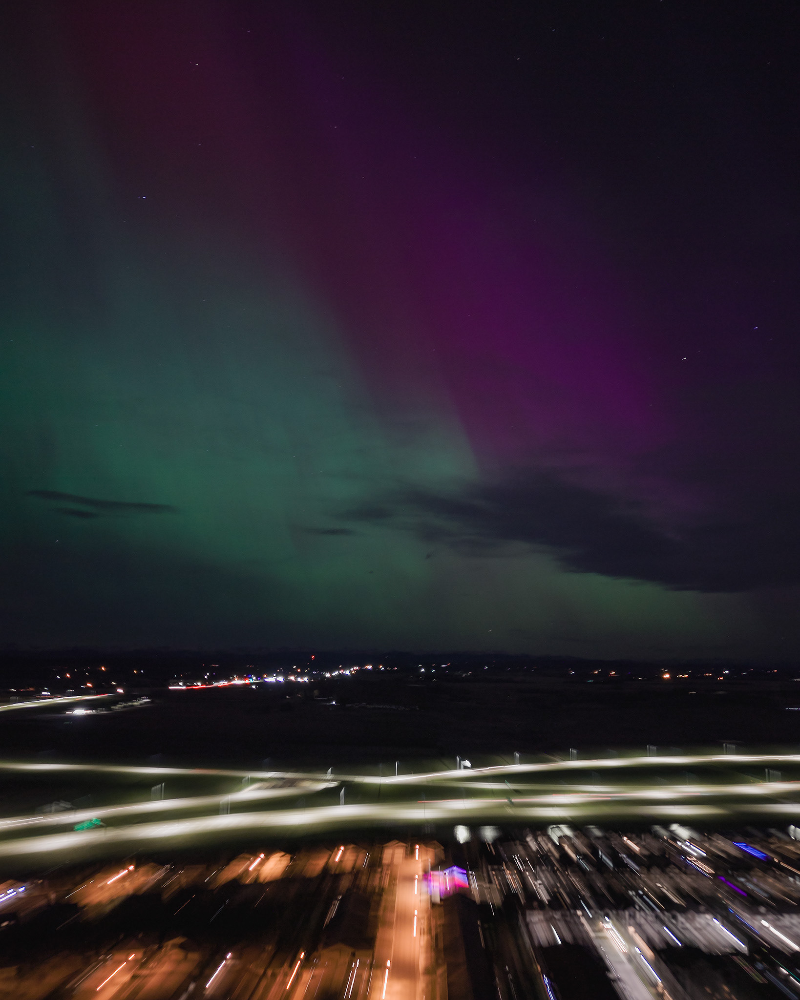 Photo of an Aurora occurrence, with motion blurred neighborhood city lights in the foreground, from Bridlewood, Calgary, AB - May 11th