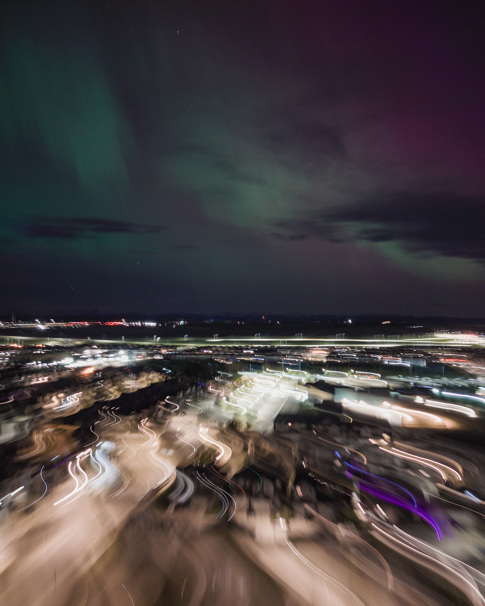 Photo of an Aurora occurrence, with motion blurred neighborhood city lights in the foreground, from Bridlewood, Calgary, AB - May 11th