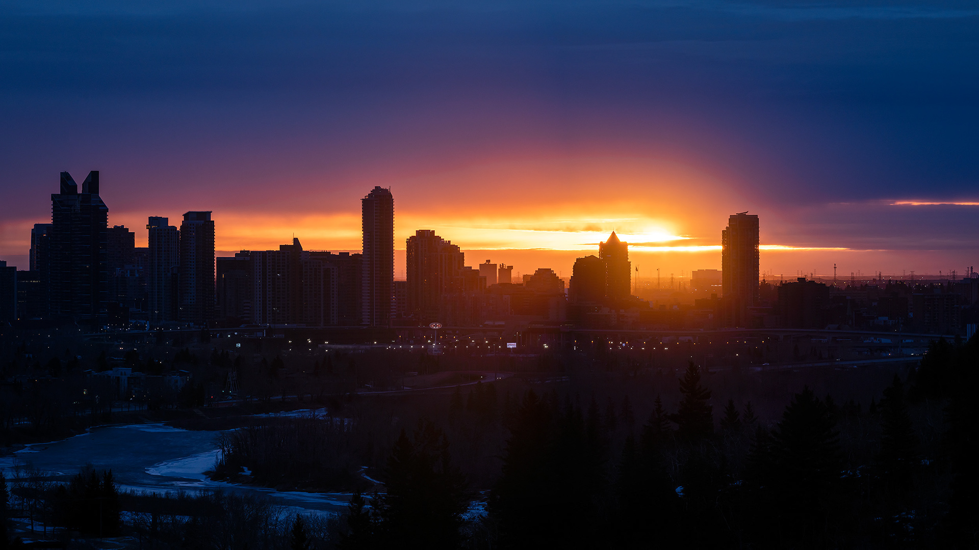 16x9 Panoramic Cityscape (5 shot) of a portion of the downtown skyline [sunrise (sun altitude 0.1 degrees)] from Edworthy Park, Calgary, AB