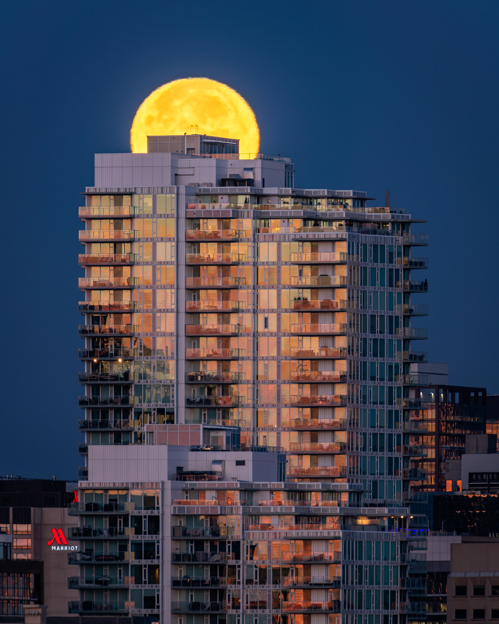 Setting Harvest Moon aligned with a Downtown East End Calgary building, from Tom Campbell's Hill Natural Park, Calgary, AB