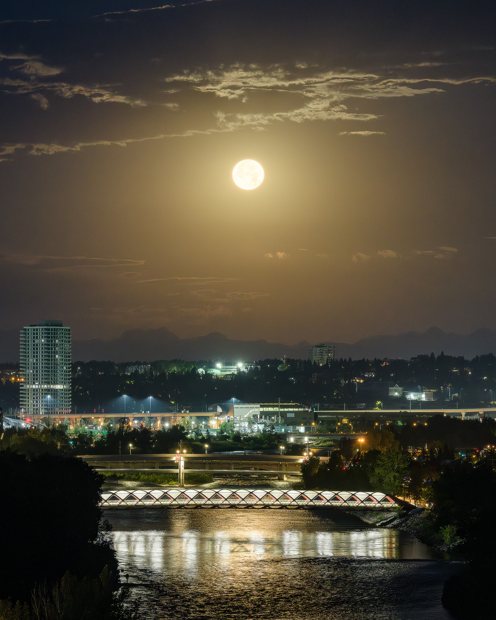 Photo of the Peace Bridge spanning the Bow River, while bathed in setting Sturgeon Moonlight, from the Crescent Heights Lookout Point, Calgary, AB - August 19th