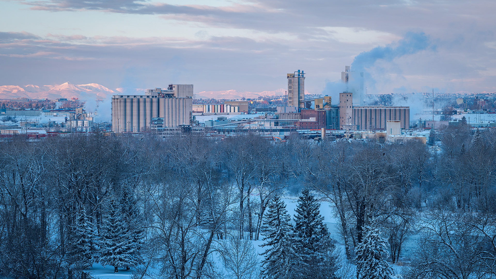 16x9 Panoramic Cityscape (6 shot) overlooking the Bow River, CP Rail Alyth Yard, and factories to the distant Rocky Mountains, from near Valleyview Park, Calgary, AB