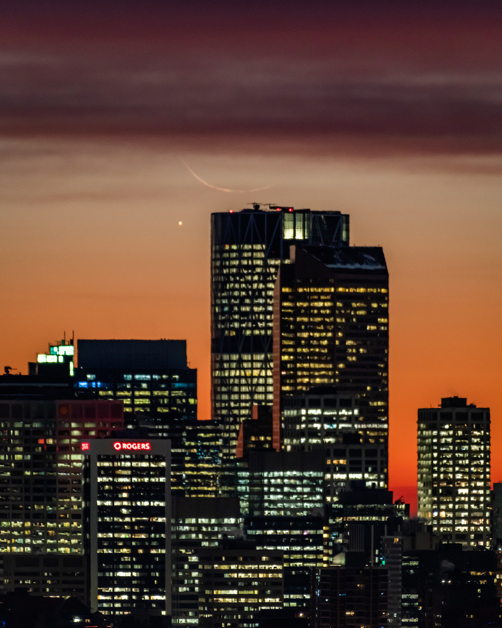 A photo of the rising Moon (Waning Crescent, 1%), and Mercury, over a portion of the Downtown Calgary skyline during Nautical Twilight (53 minutes before Sunrise), from Edworthy Park, Calgary, AB - October 24th (7:22 AM, 4:5 crop, 38 Mp)