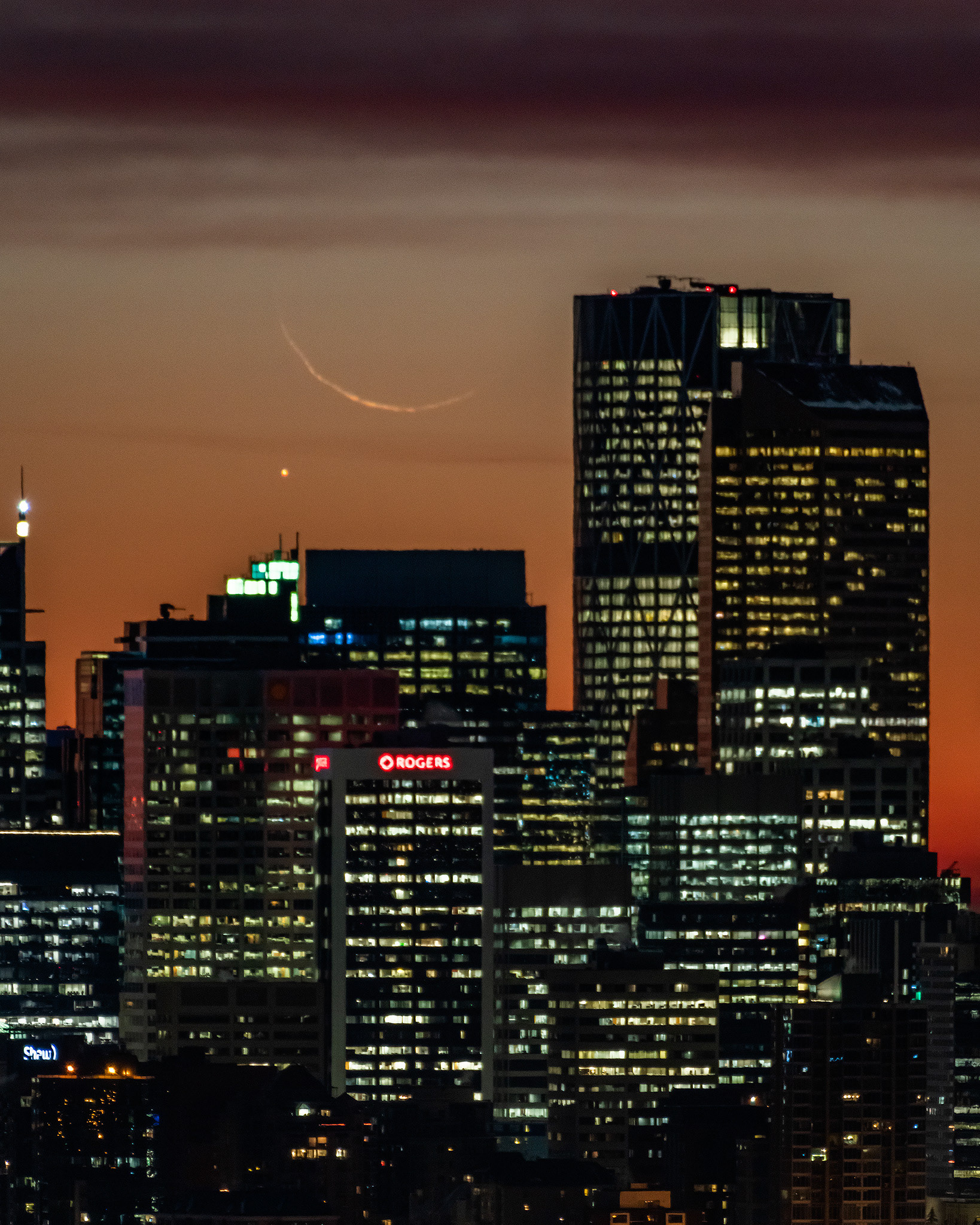 A photo of the rising Moon (Waning Crescent, 1%), and Mercury, over a portion of the Downtown Calgary skyline during Nautical Twilight (55 minutes before Sunrise), from Edworthy Park, Calgary, AB - October 24th (7:20 AM, 4:5 crop, 36 Mp)