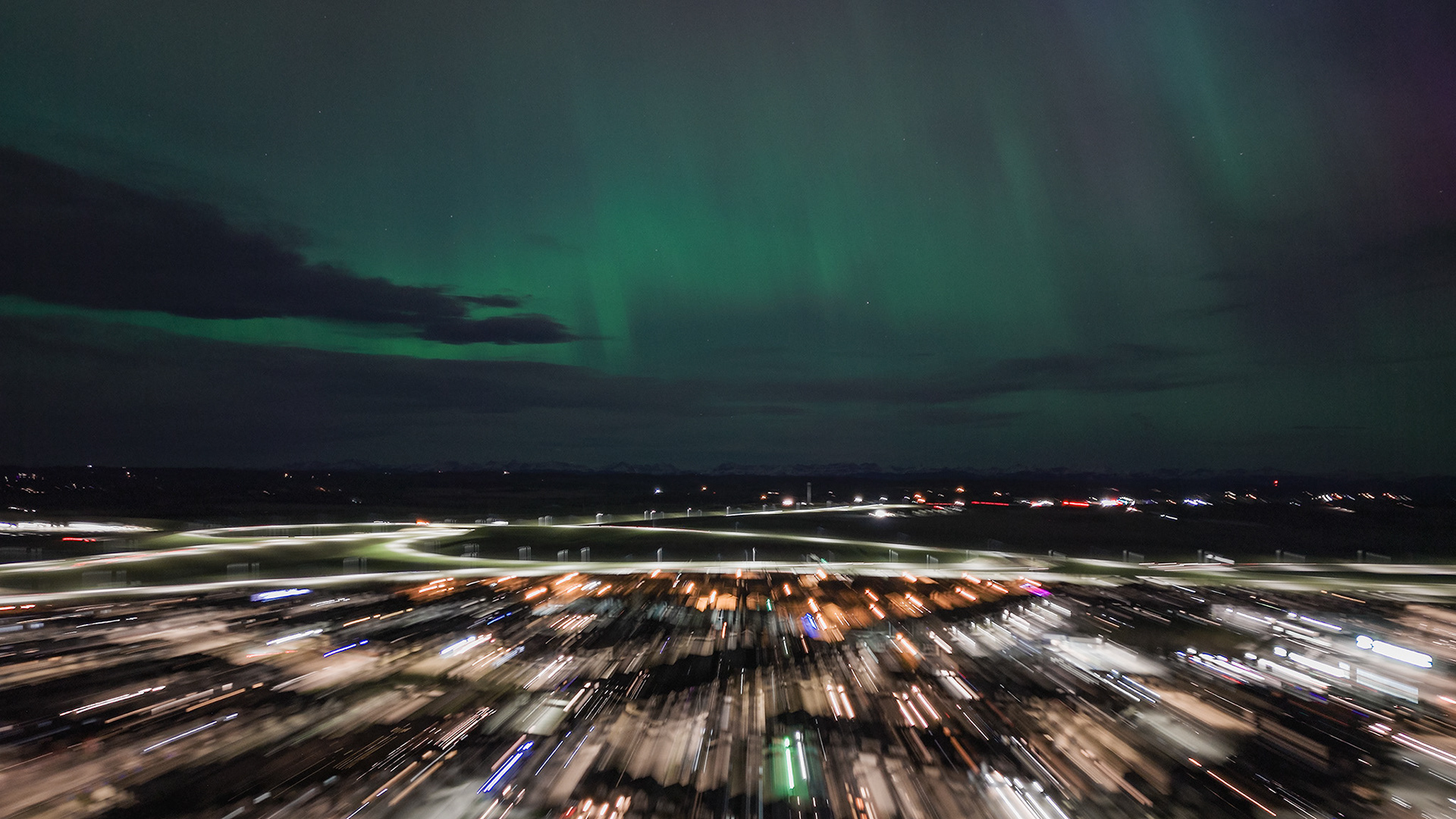 Photo of an Aurora occurrence, with motion blurred neighborhood city lights in the foreground, from Bridlewood, Calgary, AB - May 11th