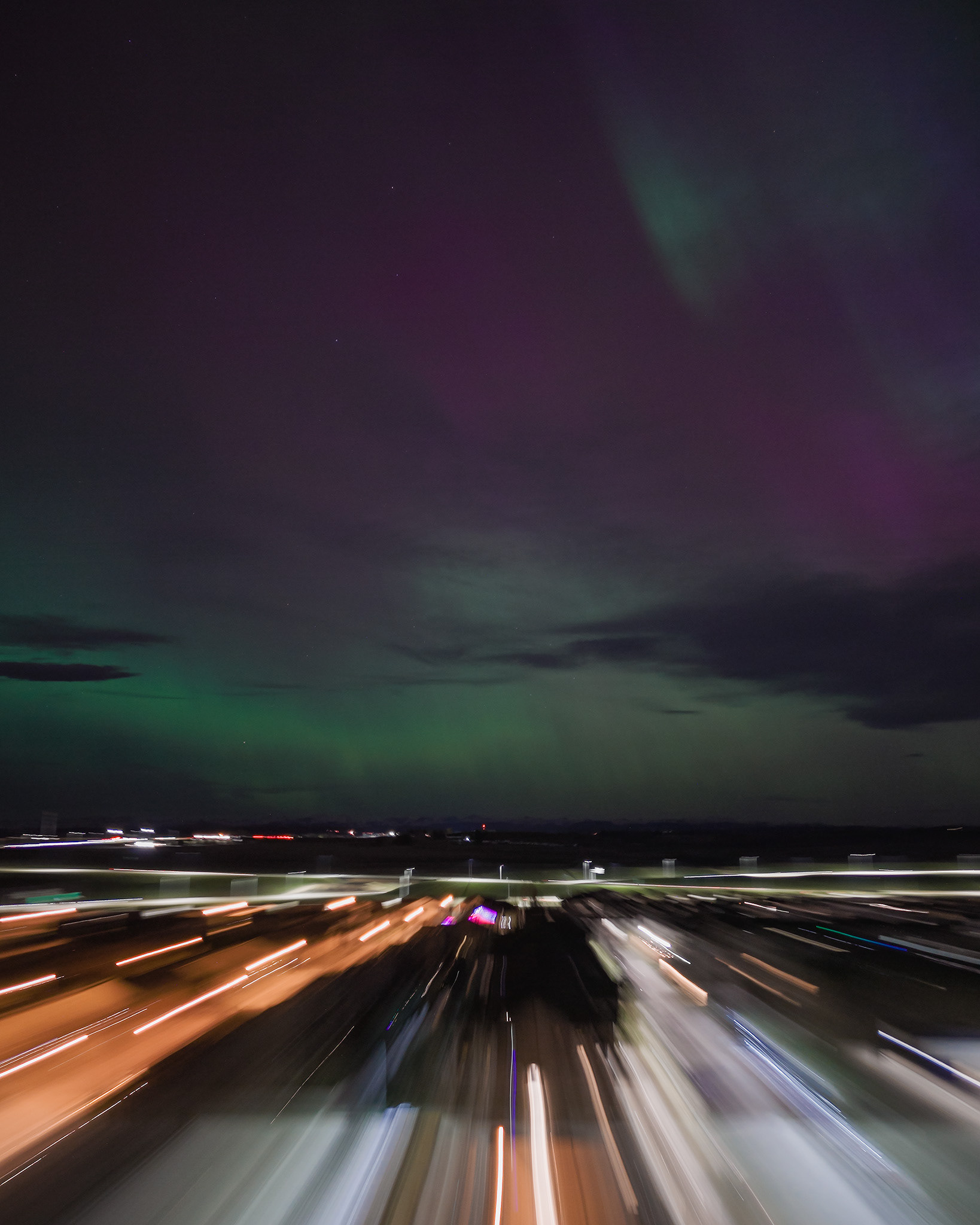 Photo of an Aurora occurrence, with motion blurred neighborhood city lights in the foreground, from Bridlewood, Calgary, AB - May 11th