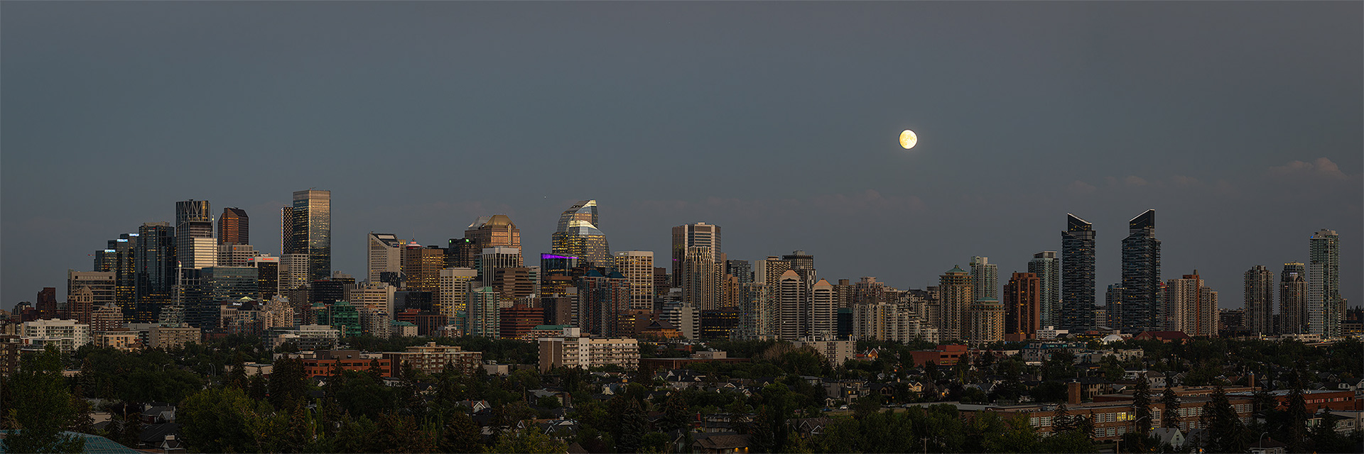 3x1 Panoramic Cityscape of the Downtown Calgary skyline at Sunset/Moonrise, from West Hillhurst off-leash area (Grasshopper Hill), Calgary, AB